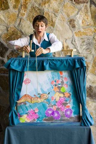 puppeteer Risa Lenore performs with a puppet of a sea creature in front of a crankie puppet theater