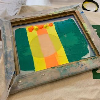 photo of screen used to print a pineapple print, covered in green yellow, and orange paint. 