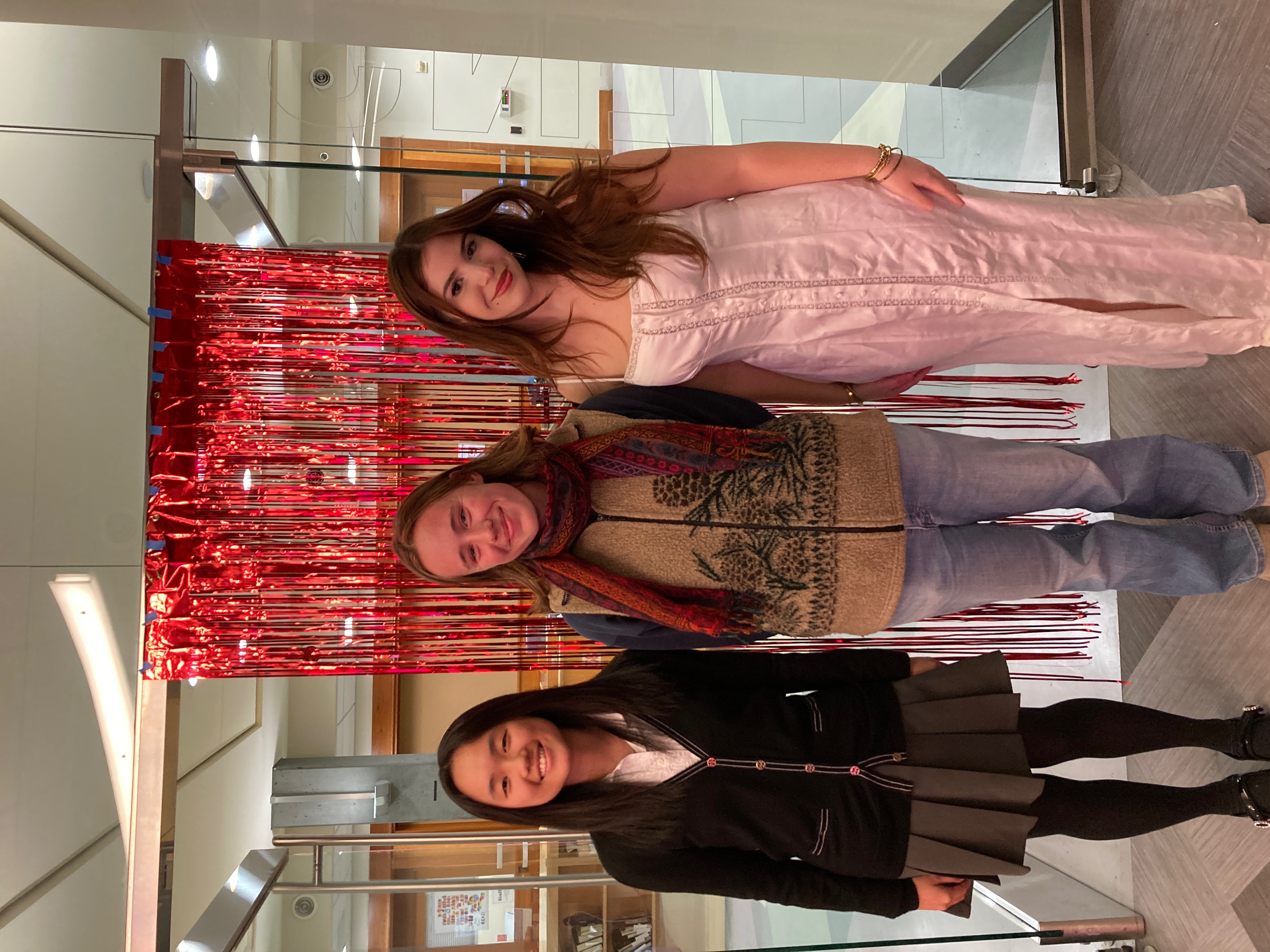 Three young women standing for a portrait in a festive room