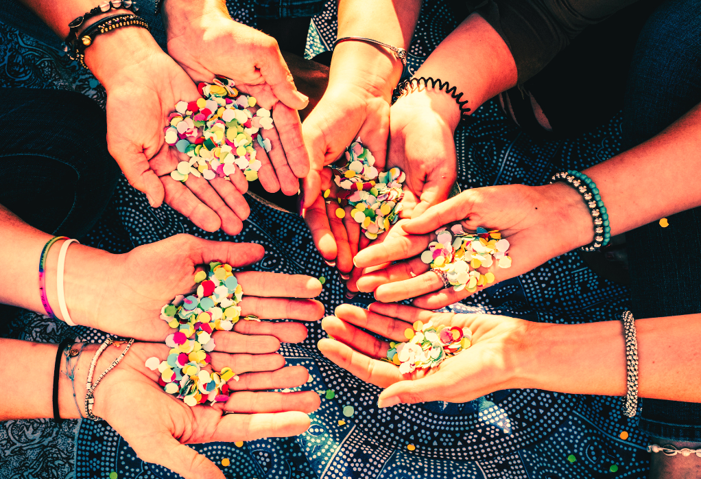 several arms outstretched, wearing beaded bracelets and holding beads in the palms