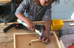 Child building with hammer and wood.