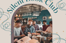 A friendly group of readers with books and mugs sit at a table. 