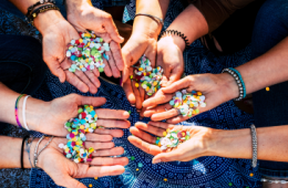 several arms outstretched with beaded bracelets on the wrists 