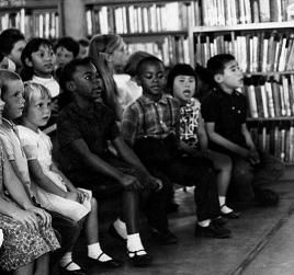Children sitting in rows in front of a wall of bookcases