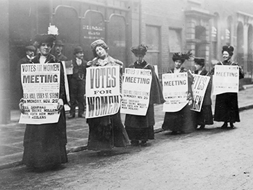 19th century period photograph of several women with signs organizing women's suffrage